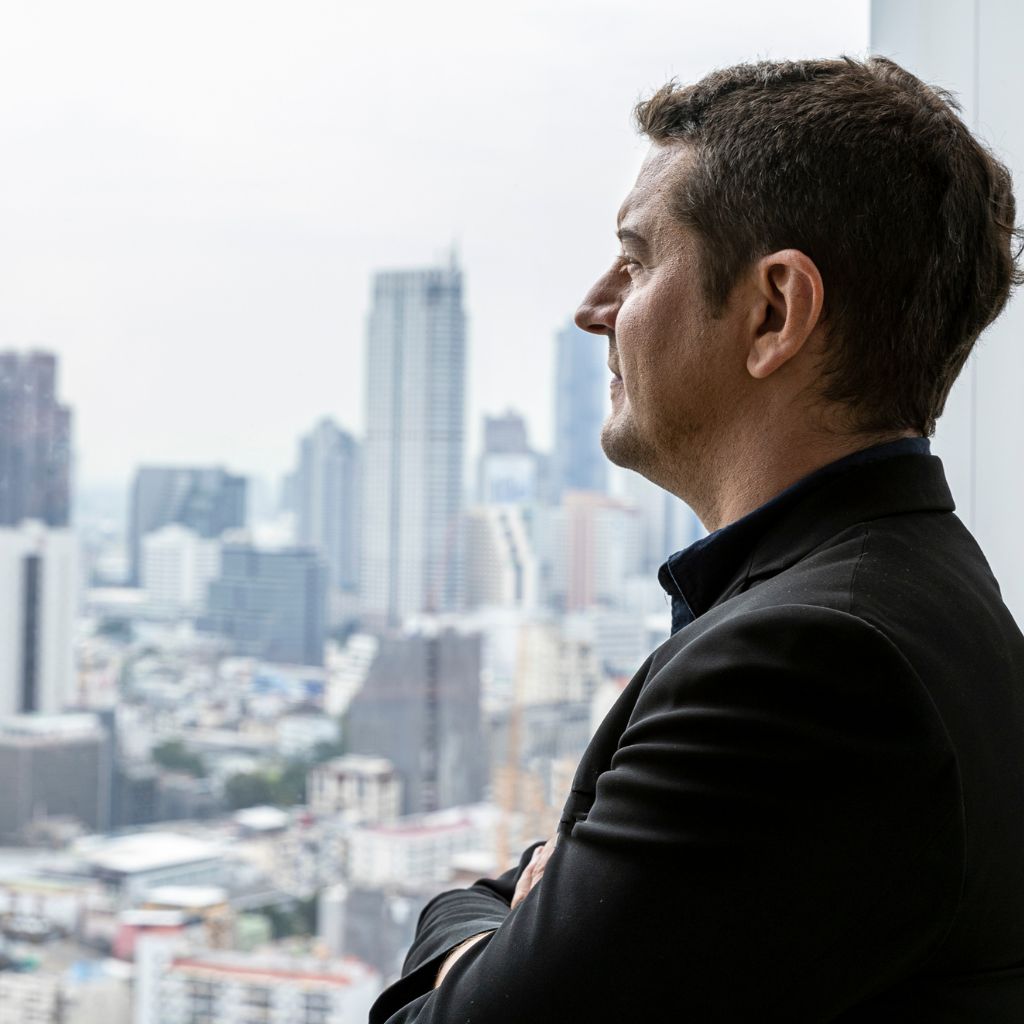 Leder som ser ut av vinduet og reflekterer over belastning og arbeidsmiljø – AMOVE Bedrift hos Utbrenthetsklinikken